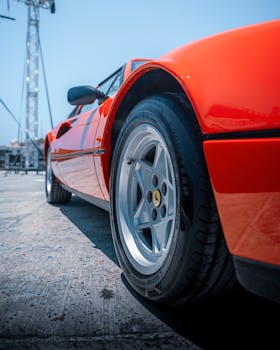 Dynamic perspective of a classic red sports car in vibrant sunlight, Alaçatı, Türkiye.
