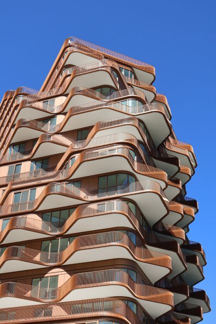 Unique wavy apartment building design under a clear blue sky in Toronto, Canada.