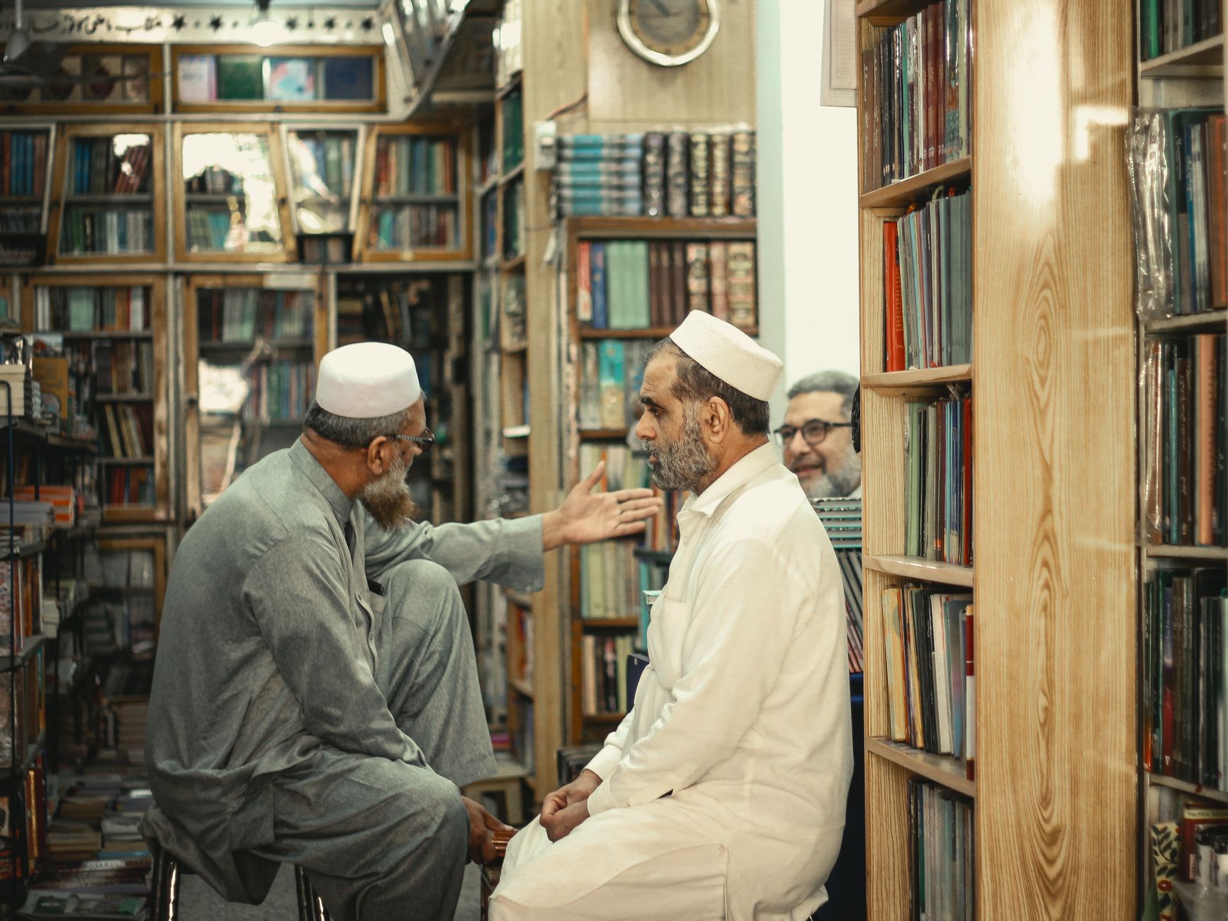 Elderly men engage in discussion inside a crowded Peshawar bookstore.