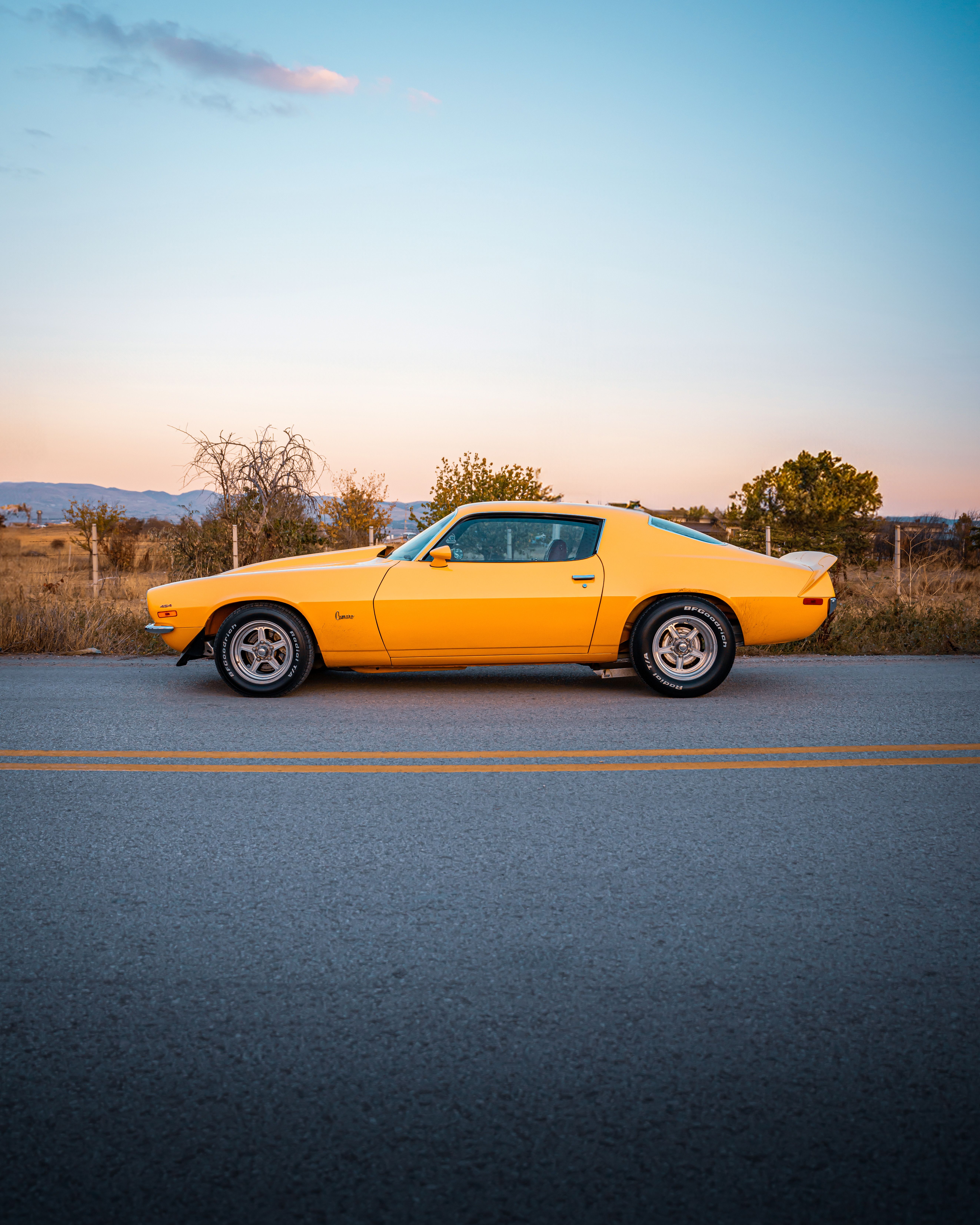 Vintage Yellow Car on Scenic Road at Dusk · Free Stock Photo