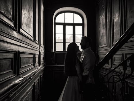 A romantic couple stands in silhouette against a classic wooden interior, suggesting timeless love.