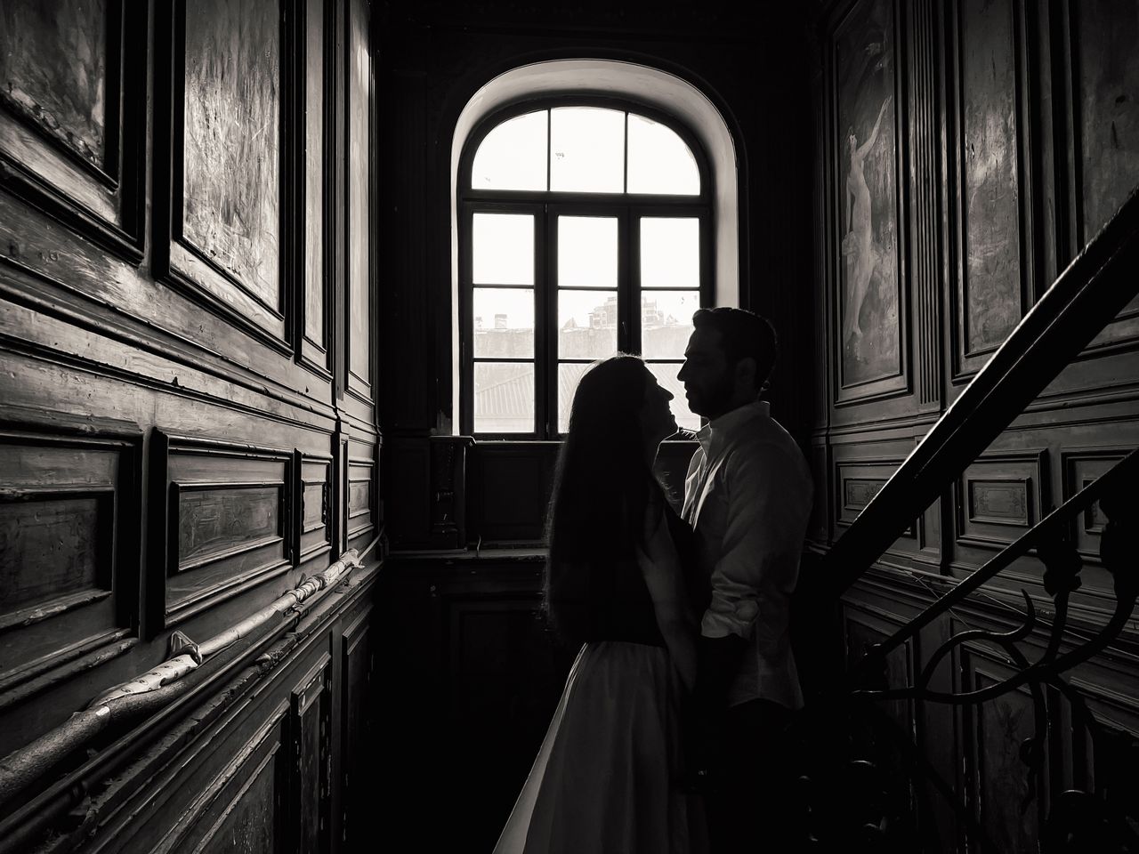 a romantic couple stands in silhouette against a classic wooden interi