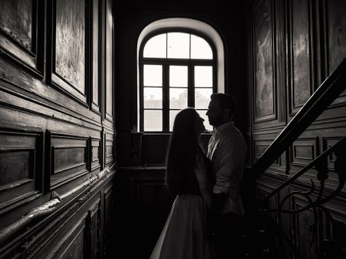 Free A romantic couple stands in silhouette against a classic wooden interior, suggesting timeless love. Stock Photo