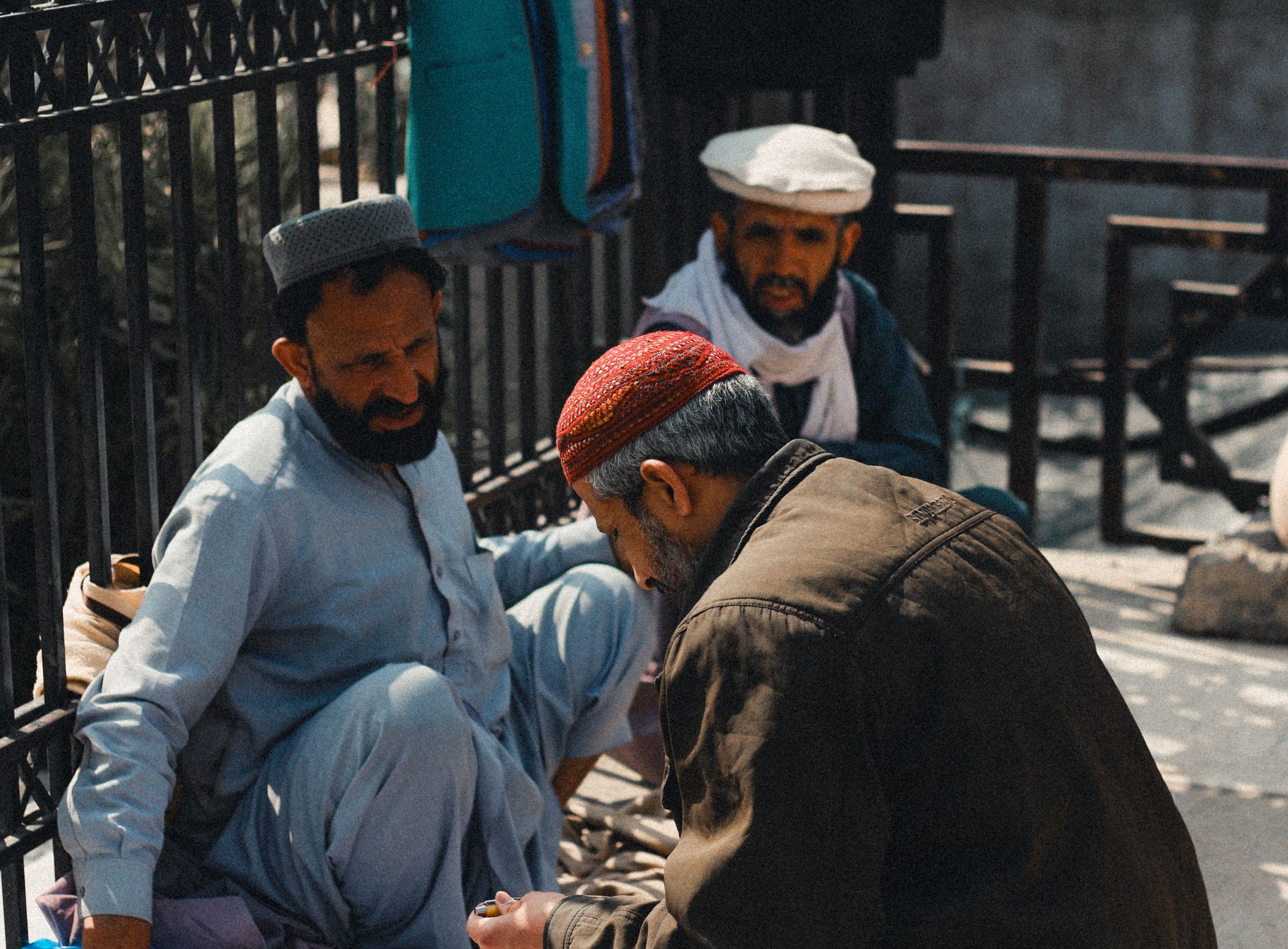 A candid street scene capturing local men in the bustling Peshawar market, highlighting cultural attire and interactions.