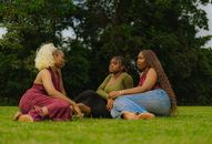A group of women enjoying a casual chat on the grass in an Abuja park.