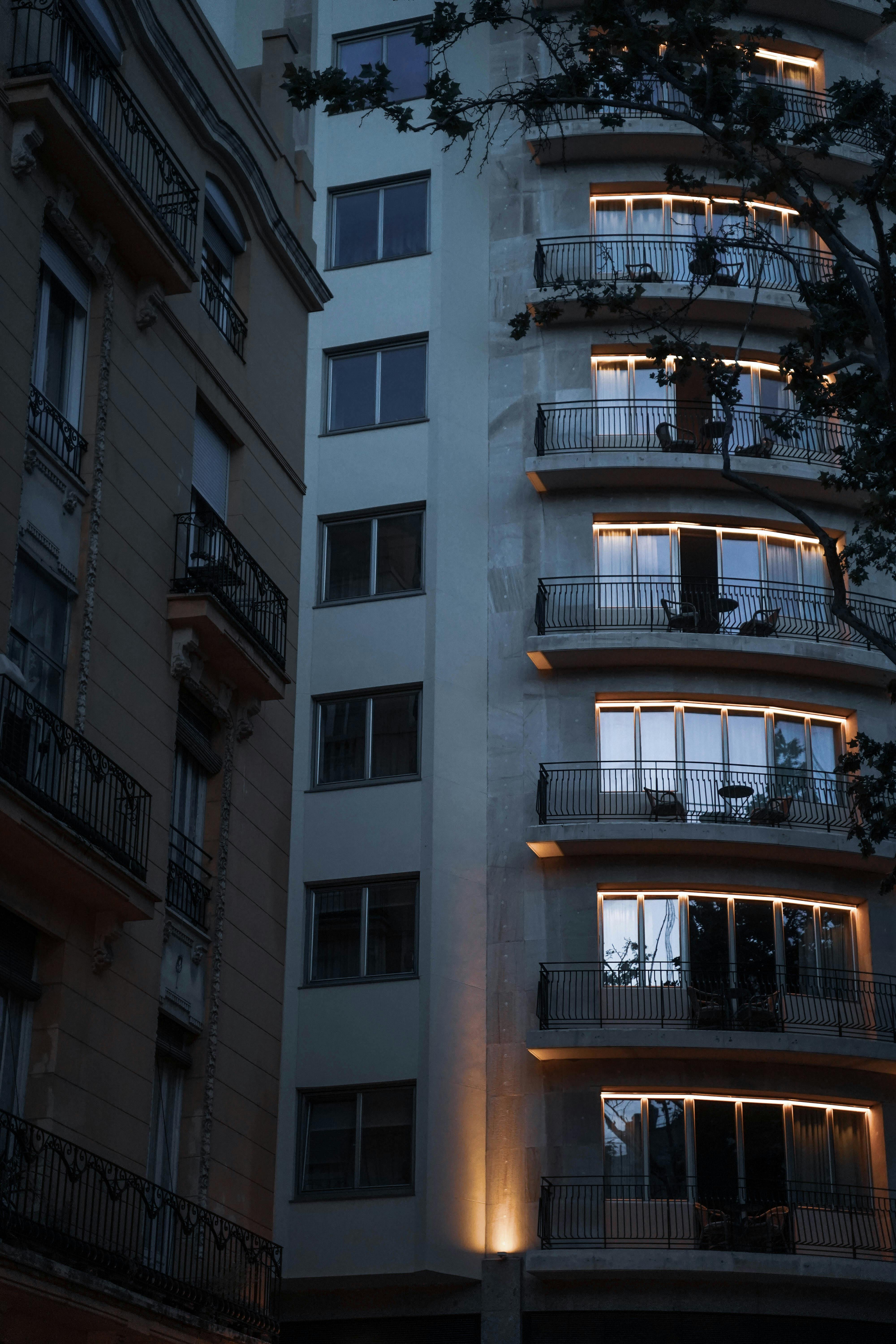 Captured at dusk, a modern residential building in Valencia, Spain with illuminated balconies and evening ambiance.