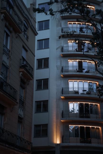 Captured at dusk, a modern residential building in Valencia, Spain with illuminated balconies and evening ambiance.