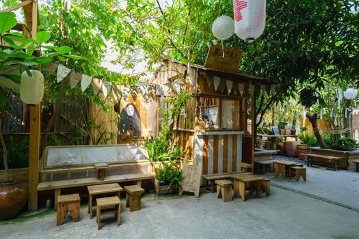 Cozy outdoor cafe with wooden decor and lush greenery. Perfect for relaxation.