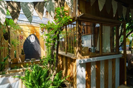 Charming garden kiosk with wooden design and lush greenery in natural sunlight.