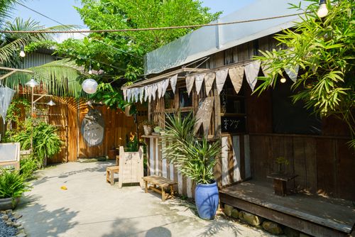 Free Cozy rustic café exterior with wooden decorations and lush greenery. Stock Photo