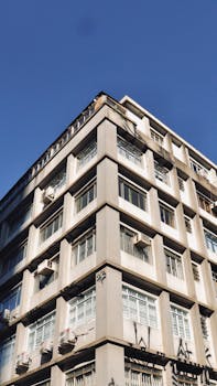 A detailed view of an urban building corner showcasing modern architecture against a clear blue sky.
