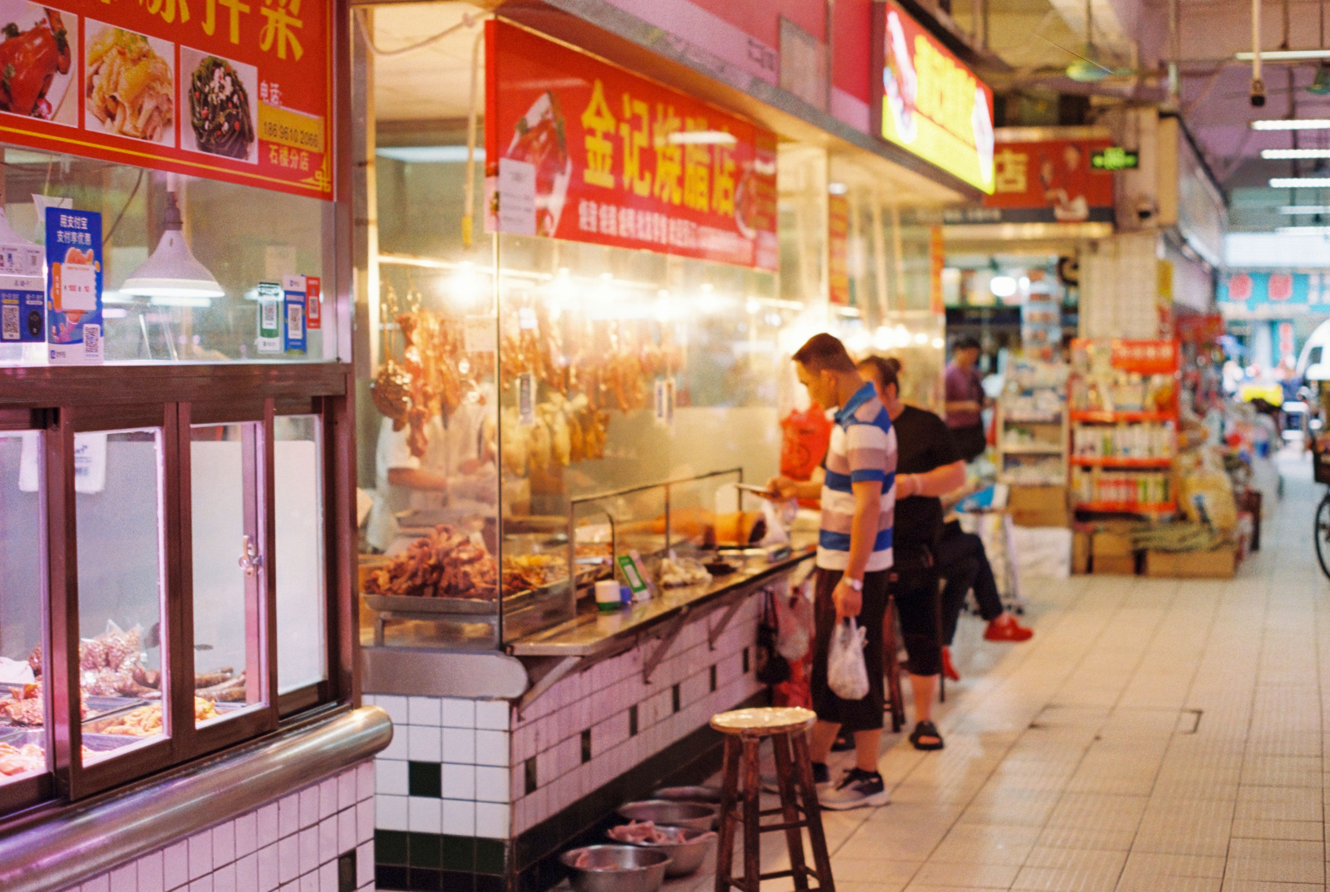 Man browsing food options at busy indoor street market stall.