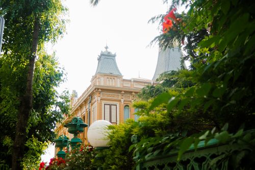 Free Victorian-style building with ornate details and vibrant greenery, captured on a sunny day. Stock Photo