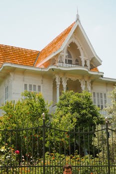 A beautiful Victorian house with intricate architecture surrounded by vibrant greenery.