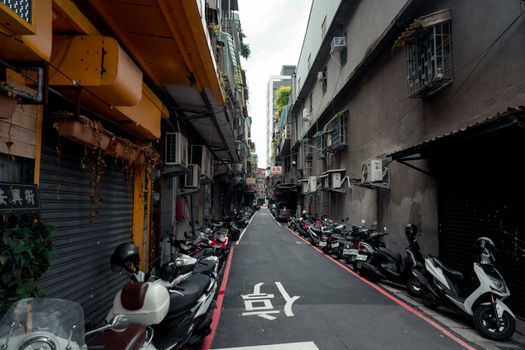 Urban alley with parked scooters and traditional buildings in New Taipei City, Taiwan.