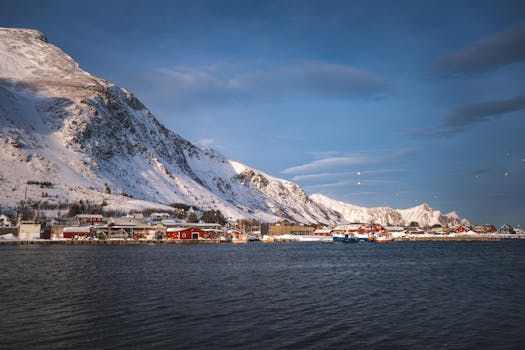 Charming village nestled by a snowy mountain, captured on a clear winter day.