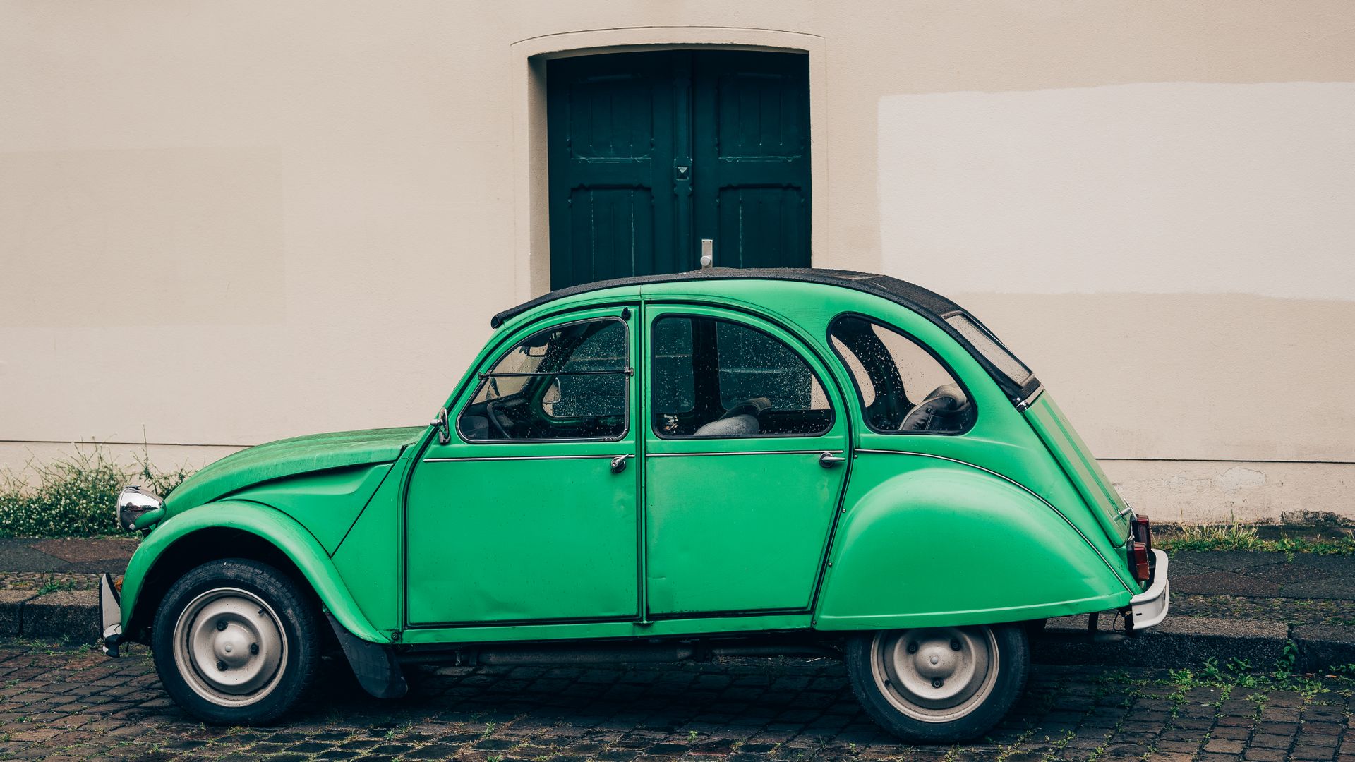Classic green car parked by an old building in Berlin, showcasing vintage automotive style.