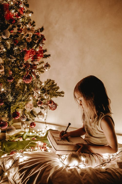 Photo De Jeune Fille Assise Près De L'arbre De Noël