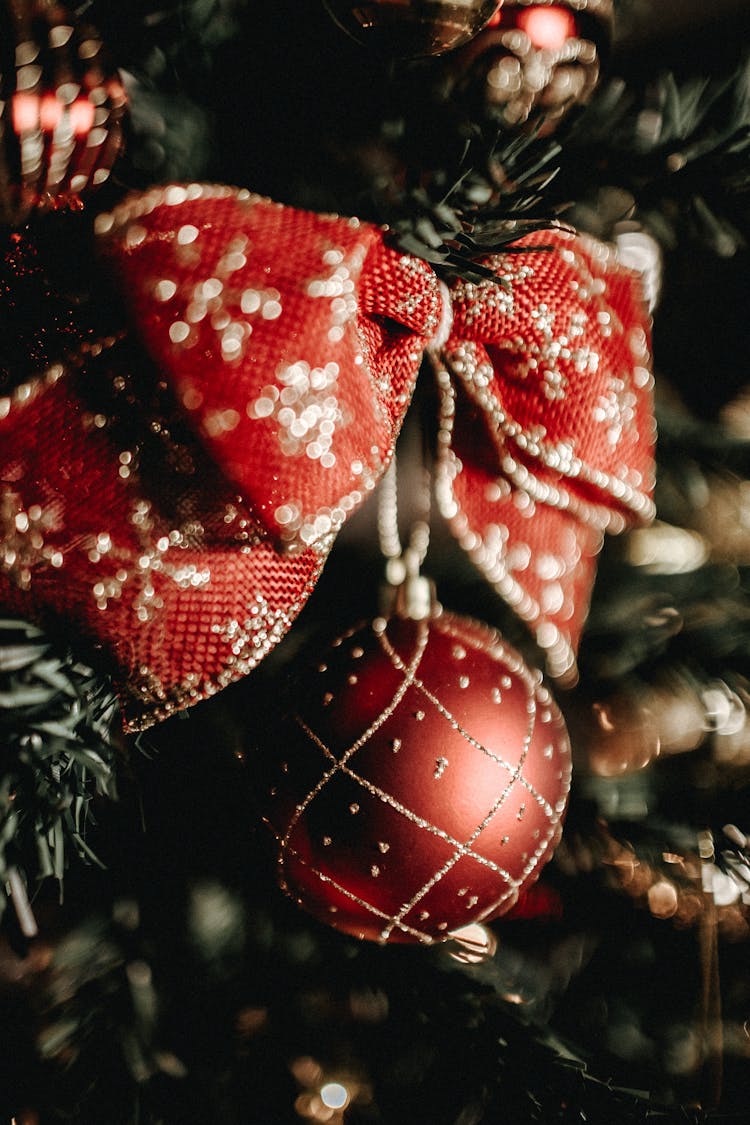 Close-up Photography Of A Red And Gold Bow Hanging On A Christmas Tree