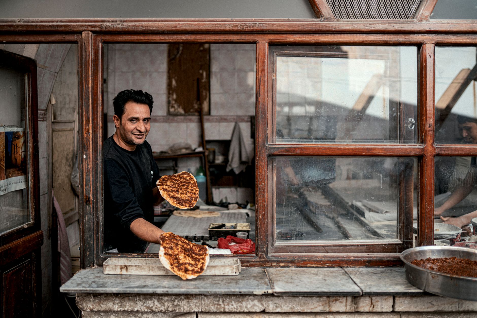 Man preparing traditional lahmacun in a rustic kitchen in Şanlıurfa, Turkey.