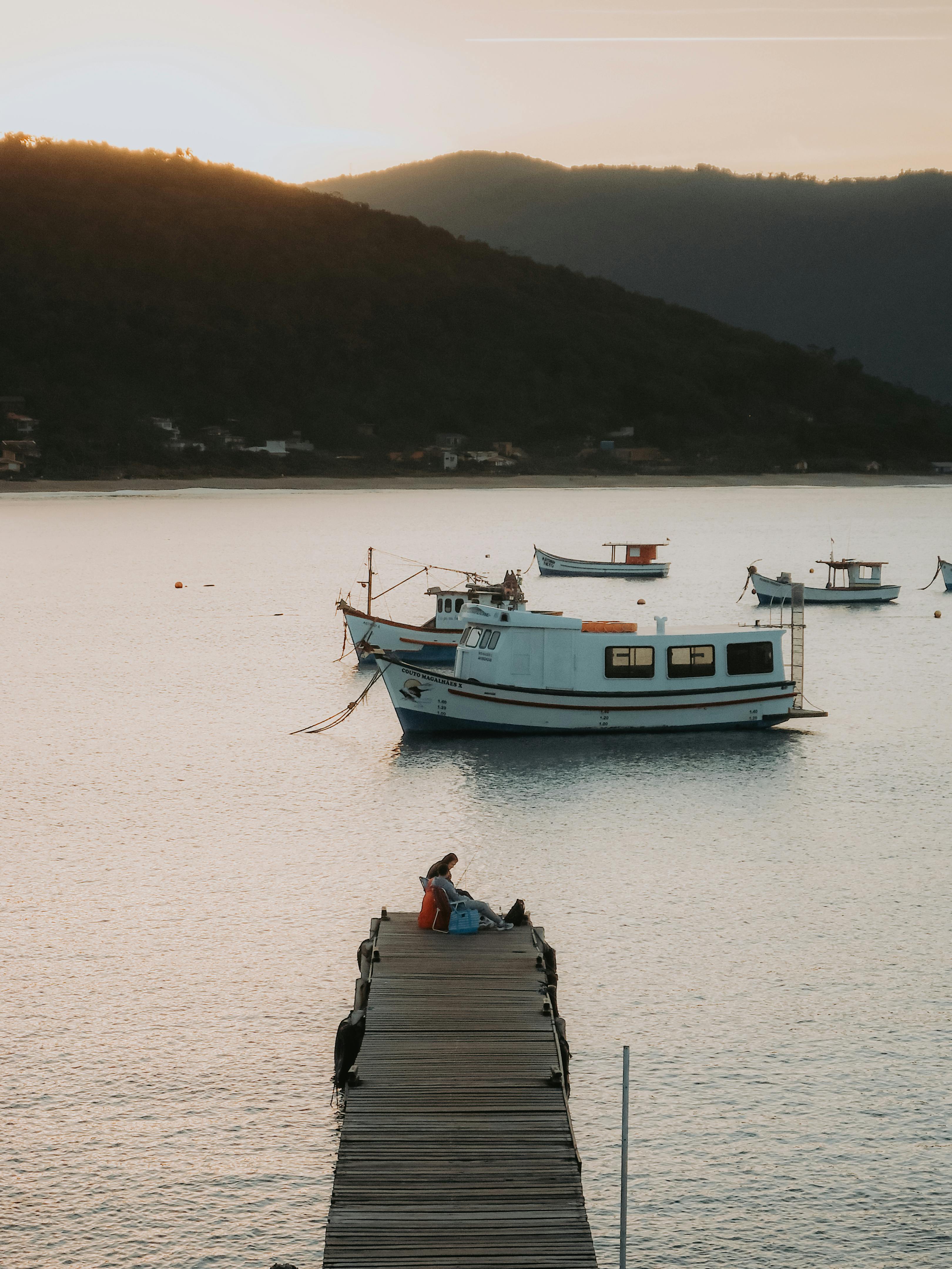 A peaceful sunset by the dock with boats floating on calm waters, creating a serene landscape.
