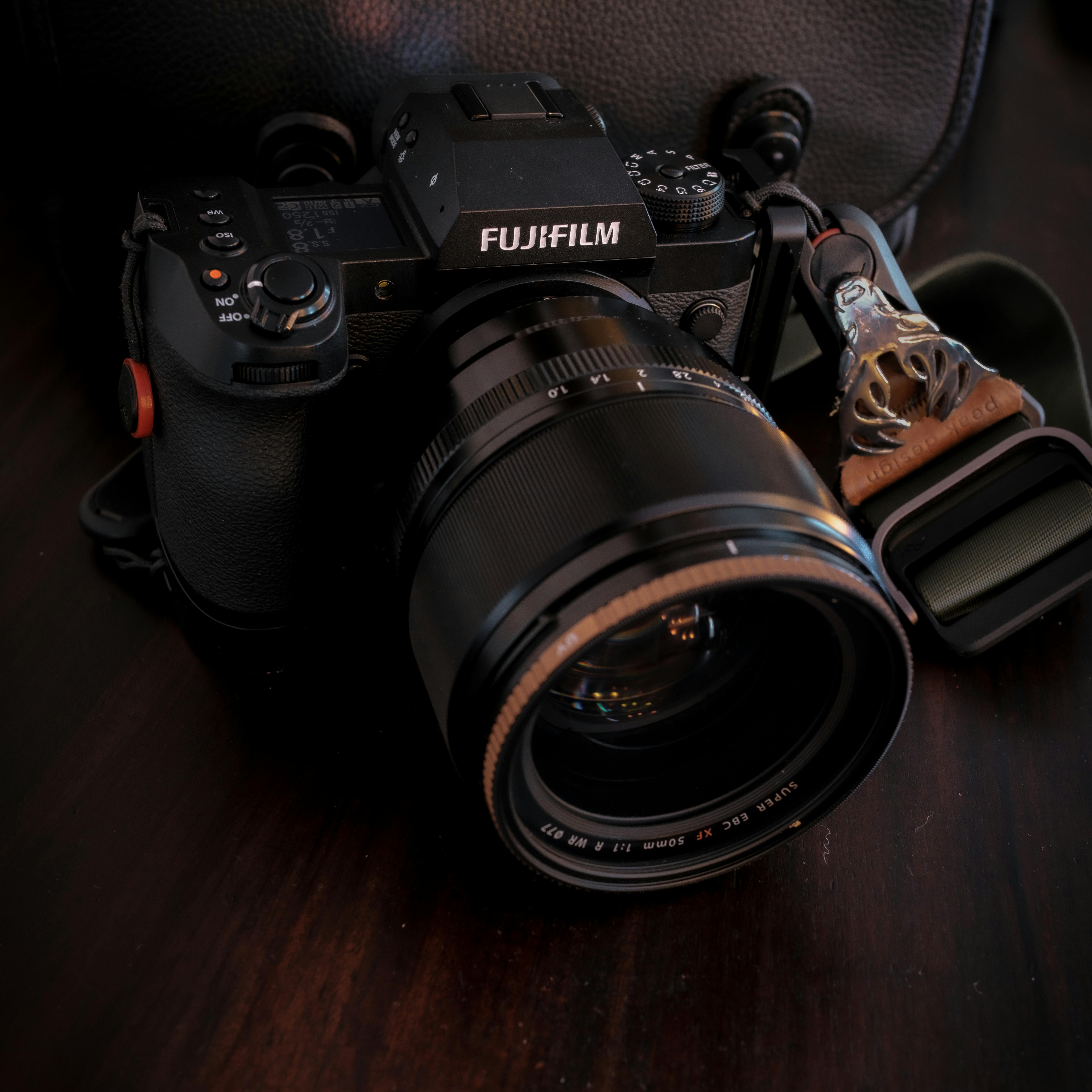 Close-up of a Fujifilm camera with 50mm lens on wooden surface.