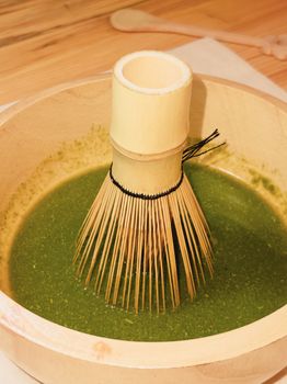 Bamboo whisk resting in bowl of freshly prepared matcha tea. Authentic and artistic.