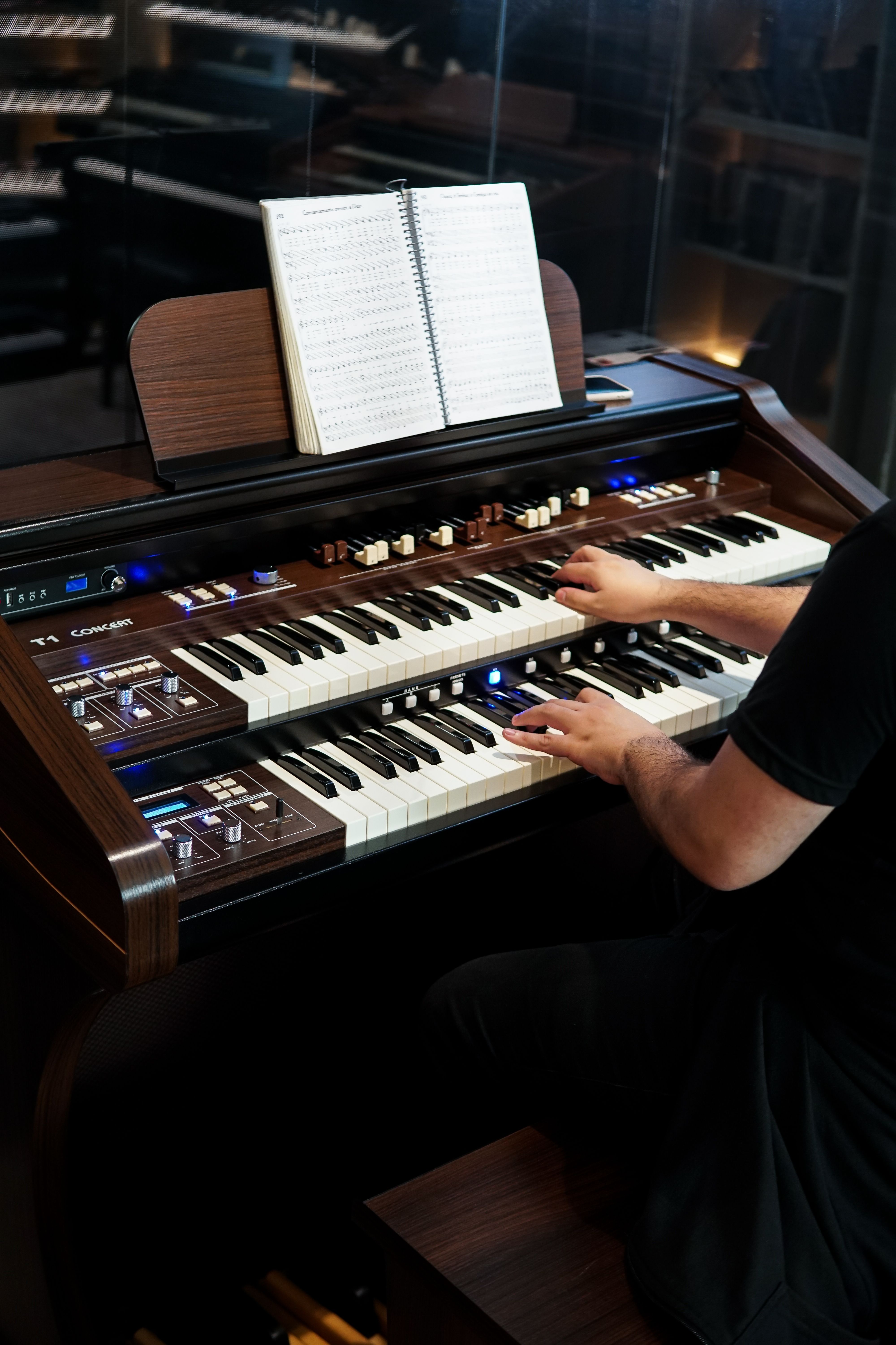 A musician playing a vintage electronic organ with a music sheet in a cozy indoor setting.