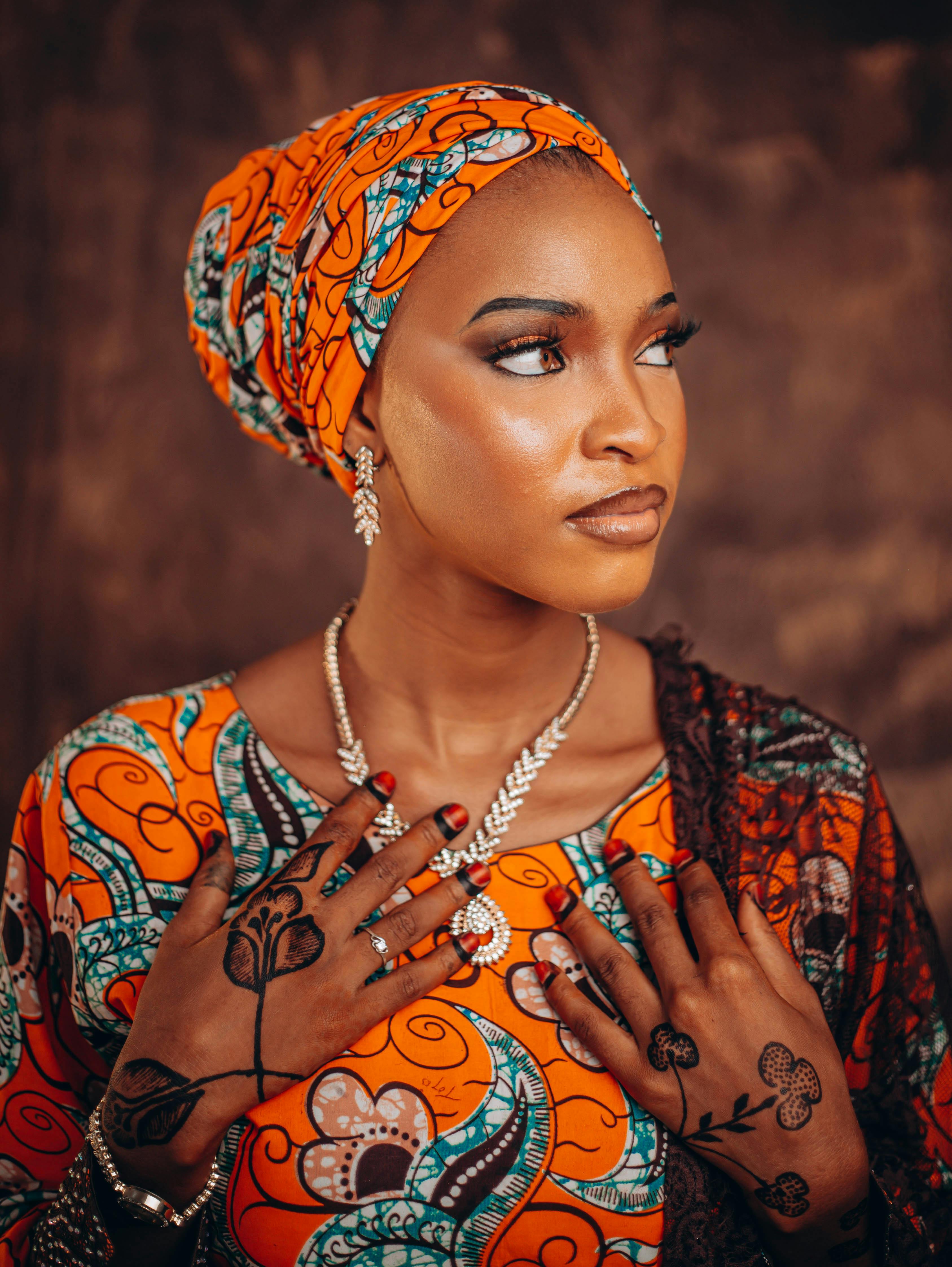 Beautiful African woman in bright traditional attire with intricate henna designs, exuding elegance.