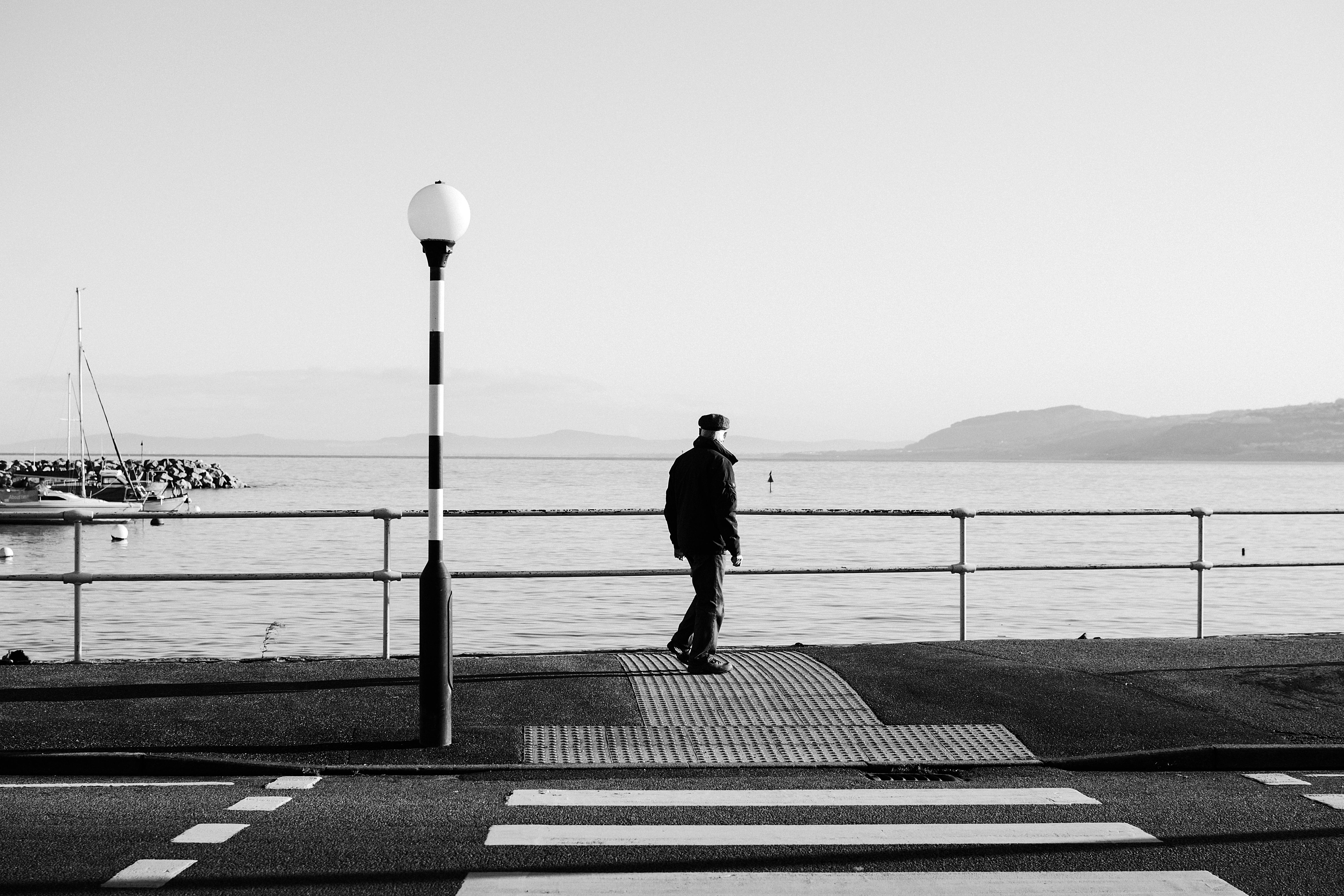 A person wearing a mask standing on a sidewalk photo – Free