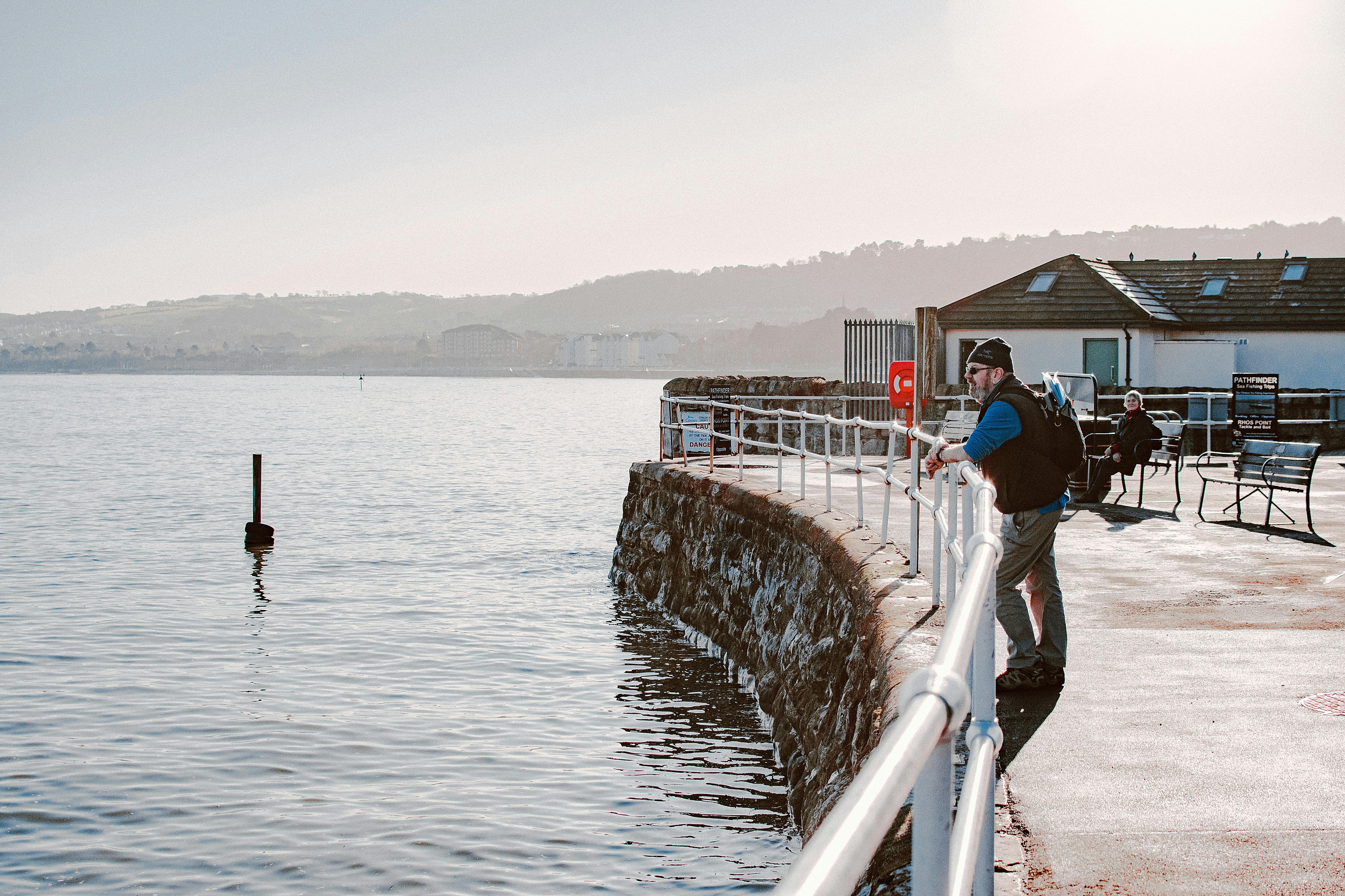 A peaceful morning scene at Rhos on Sea, showing people relaxing by the seaside promenade.