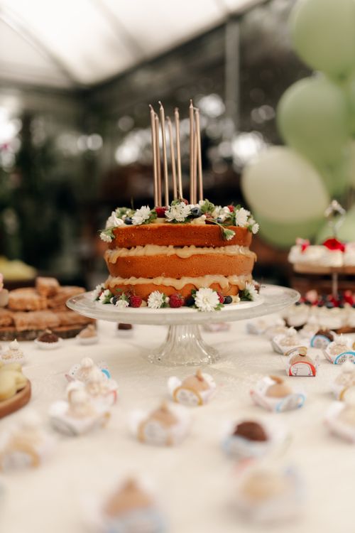 Free Layered cake with candles on display surrounded by festive treats and balloons. Stock Photo