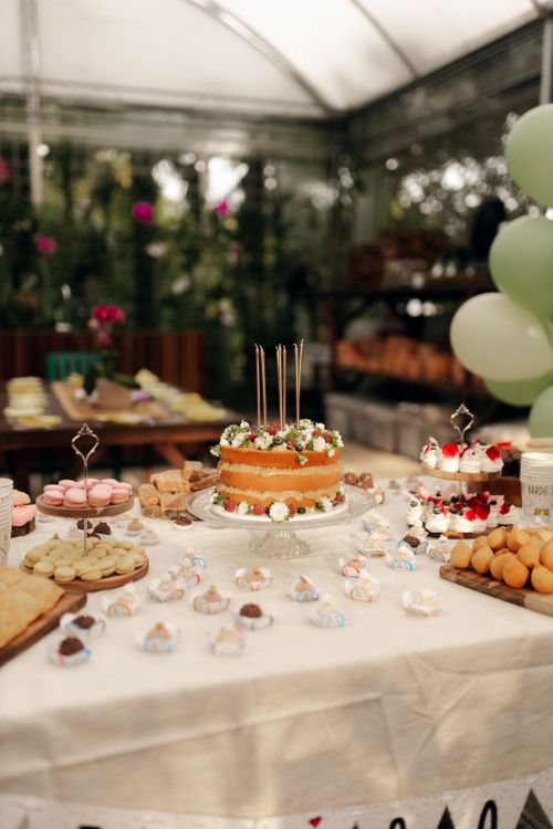Free Festive dessert table with cake, macarons, and treats in a bright outdoor setting. Perfect for parties and celebrations. Stock Photo