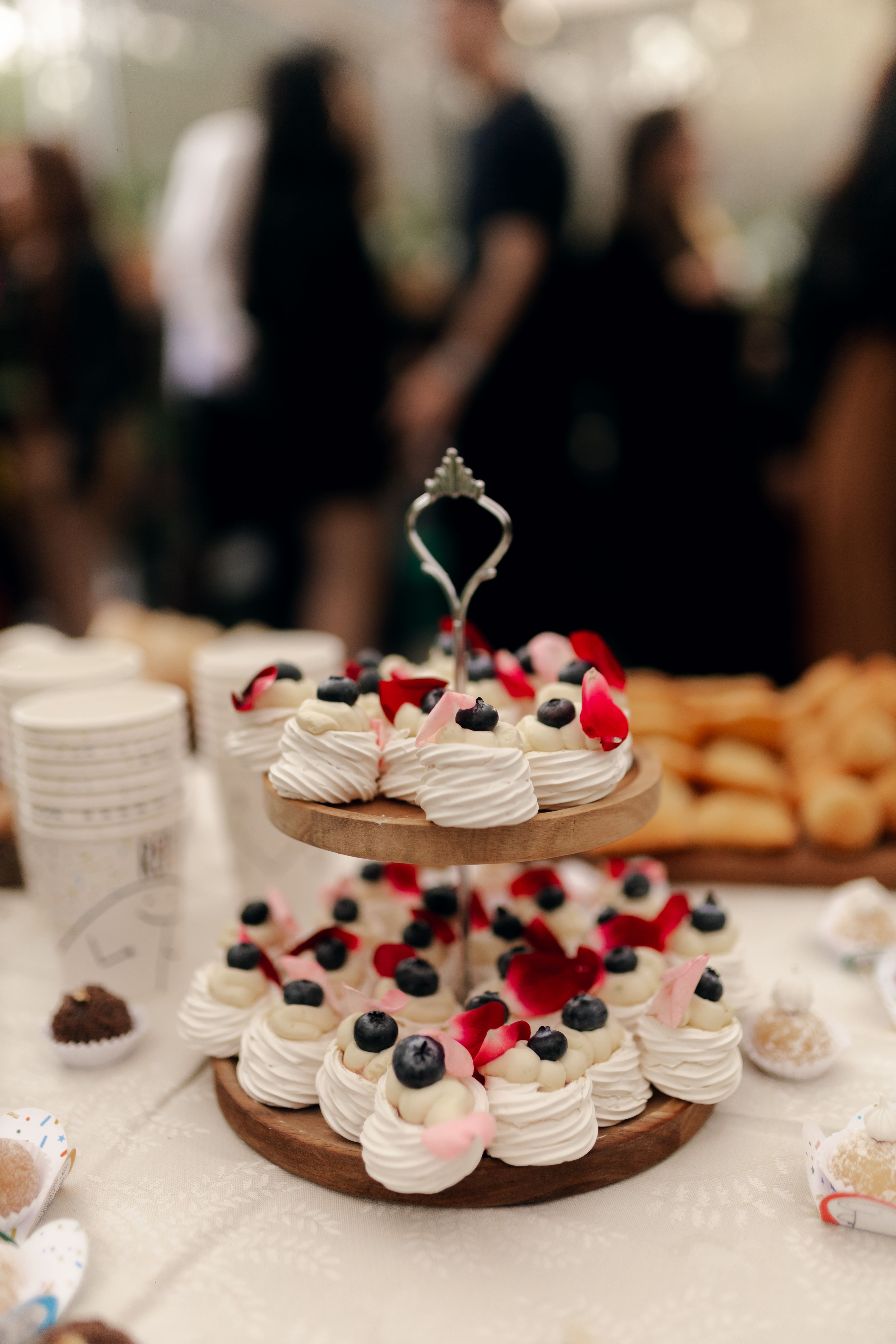 A lavish dessert display featuring pavlovas topped with blueberries and rose petals, perfect for celebrations and events.