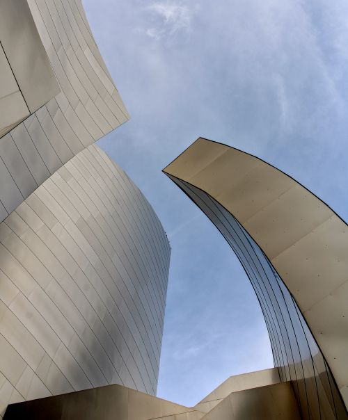 Free Striking modern architecture with curved metallic surfaces and a clear blue sky background. Stock Photo