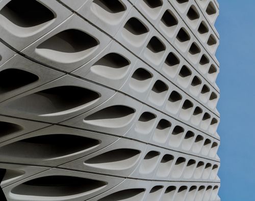 Free Close-up of a modern building's geometric and abstract façade against a clear blue sky. Stock Photo