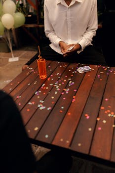 A stylish party setup with playing cards and colorful confetti on a wooden table.