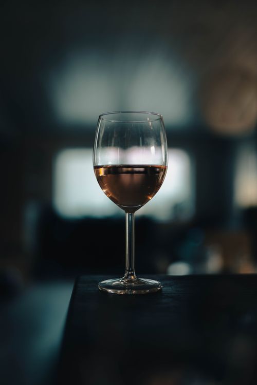 Free A glass of rosé wine in a dimly lit room creating a moody ambiance. Stock Photo