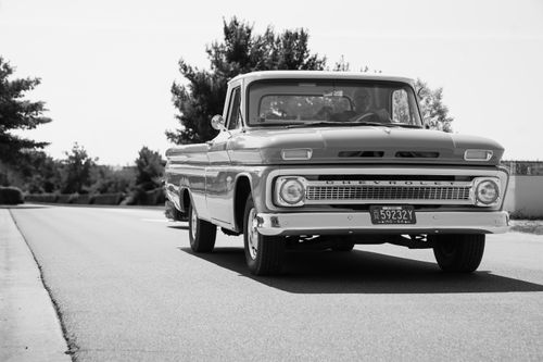 Free A vintage Chevrolet truck driving on a sunny road in a classic black and white setting. Stock Photo