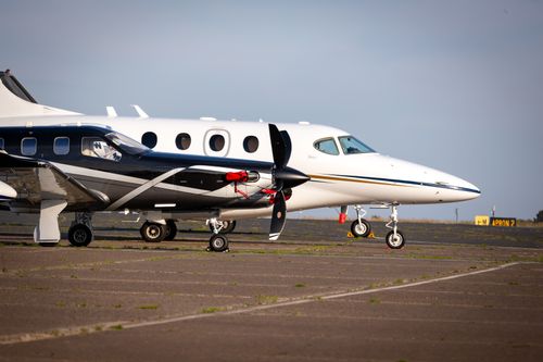 Free Luxury private aircraft parked on an airport tarmac, ready for departure under clear blue skies. Stock Photo