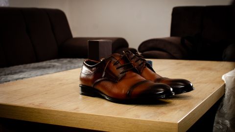 Stylish brown leather shoes placed on a wooden table in a cozy indoor setting.