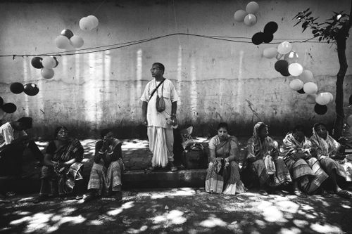 Free Traditional people seated in a Kolkata street with festive balloons above. Stock Photo