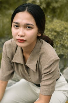 一位表情安详的女人坐在户外，在自然光线下被捕捉，显得深思熟虑