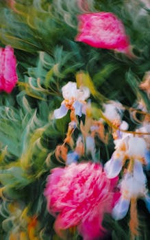 A dynamic abstract blur of vibrant pink and white flowers with swirling green leaves.