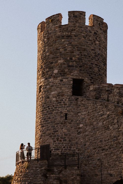 Free A medieval stone tower with two people standing at sunset, capturing historical architecture. Stock Photo