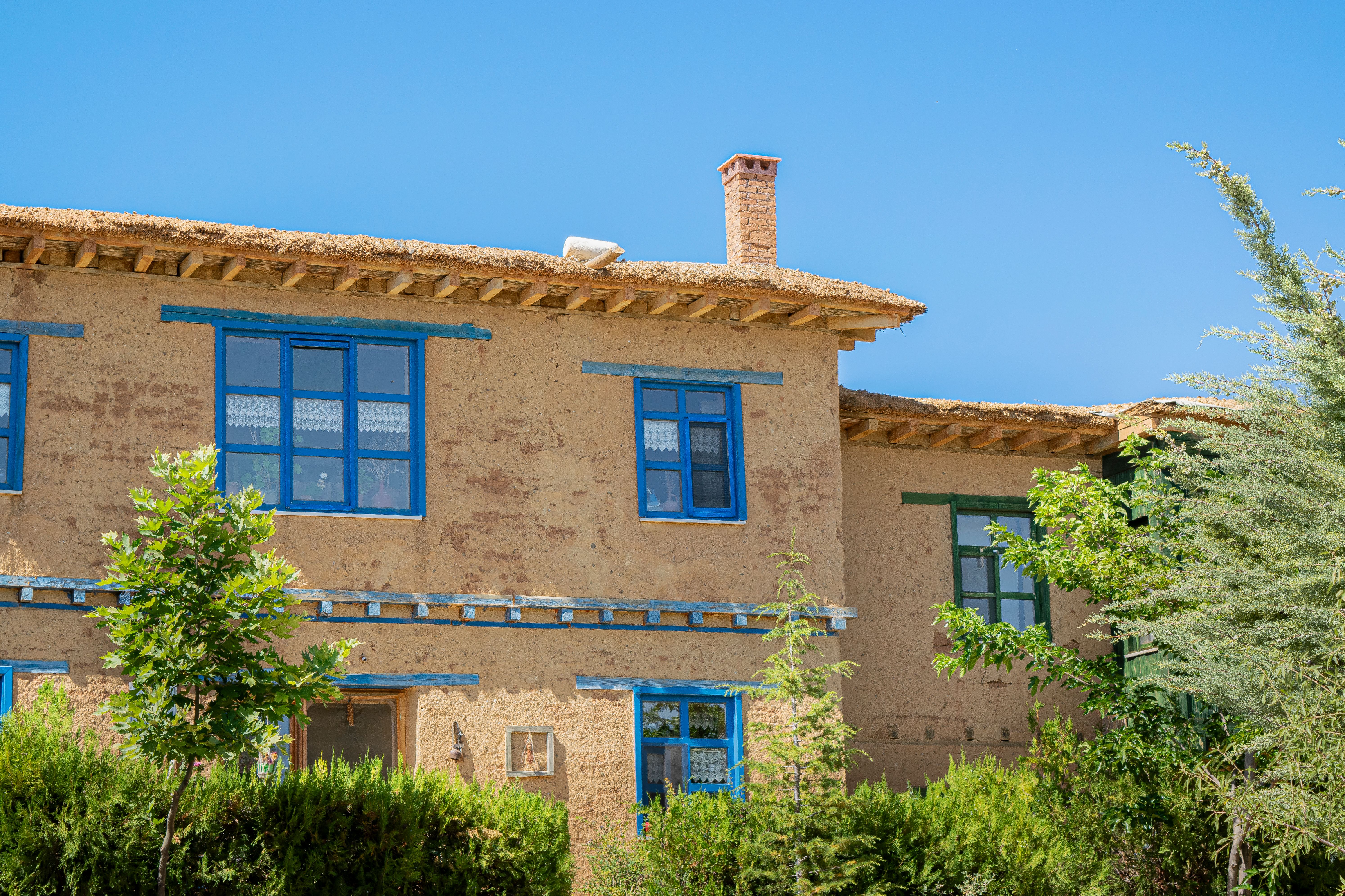 Rustic Clay House with Blue Windows in Sunny Setting · Free Stock Photo
