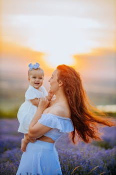 A joyful moment of a mother holding her baby in a lavender field during sunset.