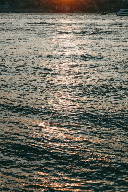 Free Tranquil photograph capturing the serene ocean waves under a warm, setting sun. Stock Photo