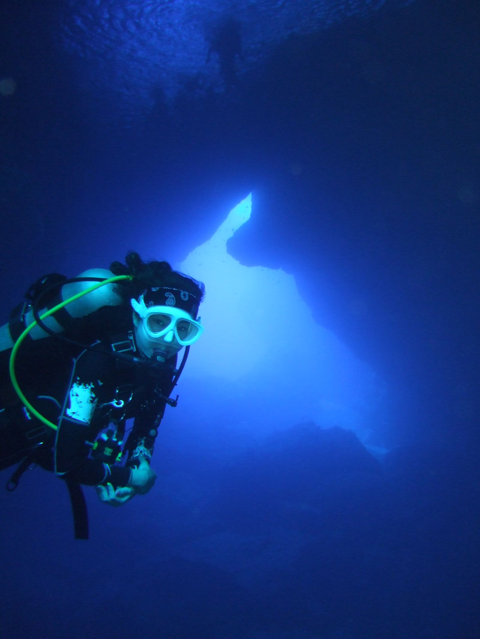 A diver exploring an underwater cave with a glowing blue backdrop