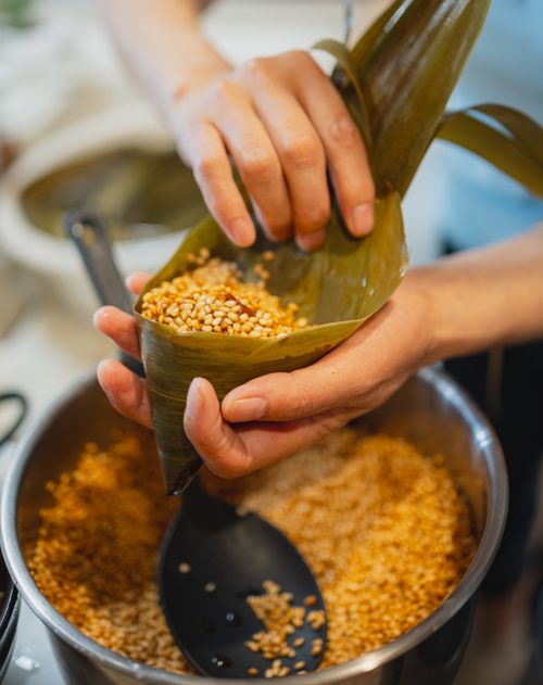 Free Hand wrapping a traditional Japanese rice dumpling in bamboo leaf, showing culinary craftsmanship. Stock Photo